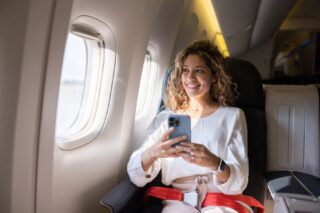 A happy female passenger sitting in a window seat on a plane