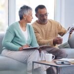 a mixed-raced couple sitting on their sofa researching international health insurance options