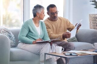 a mixed-raced couple sitting on their sofa researching international health insurance options