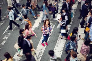 a caesarean girl standing still in the middle of a crowded crossing in Japan, feeling overwhelmed by culture shock