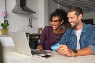 a happy couple sitting at their laptop researching the best international credit cards for living abroad