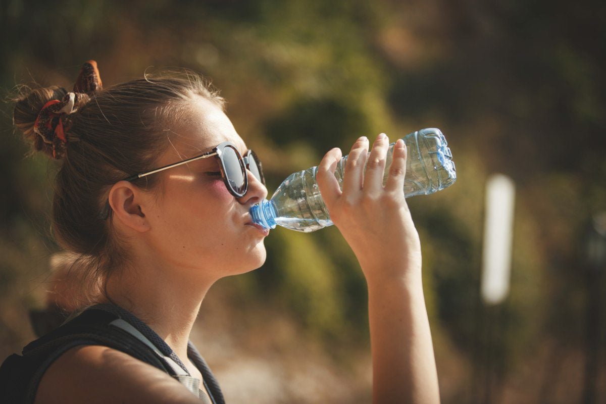 a woman drinking water from a bottle on a hot, sunny day, having read our international healthcare tips for staying healthy abroad