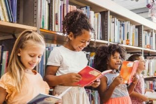 Young children studying abroad, reading books in a school library