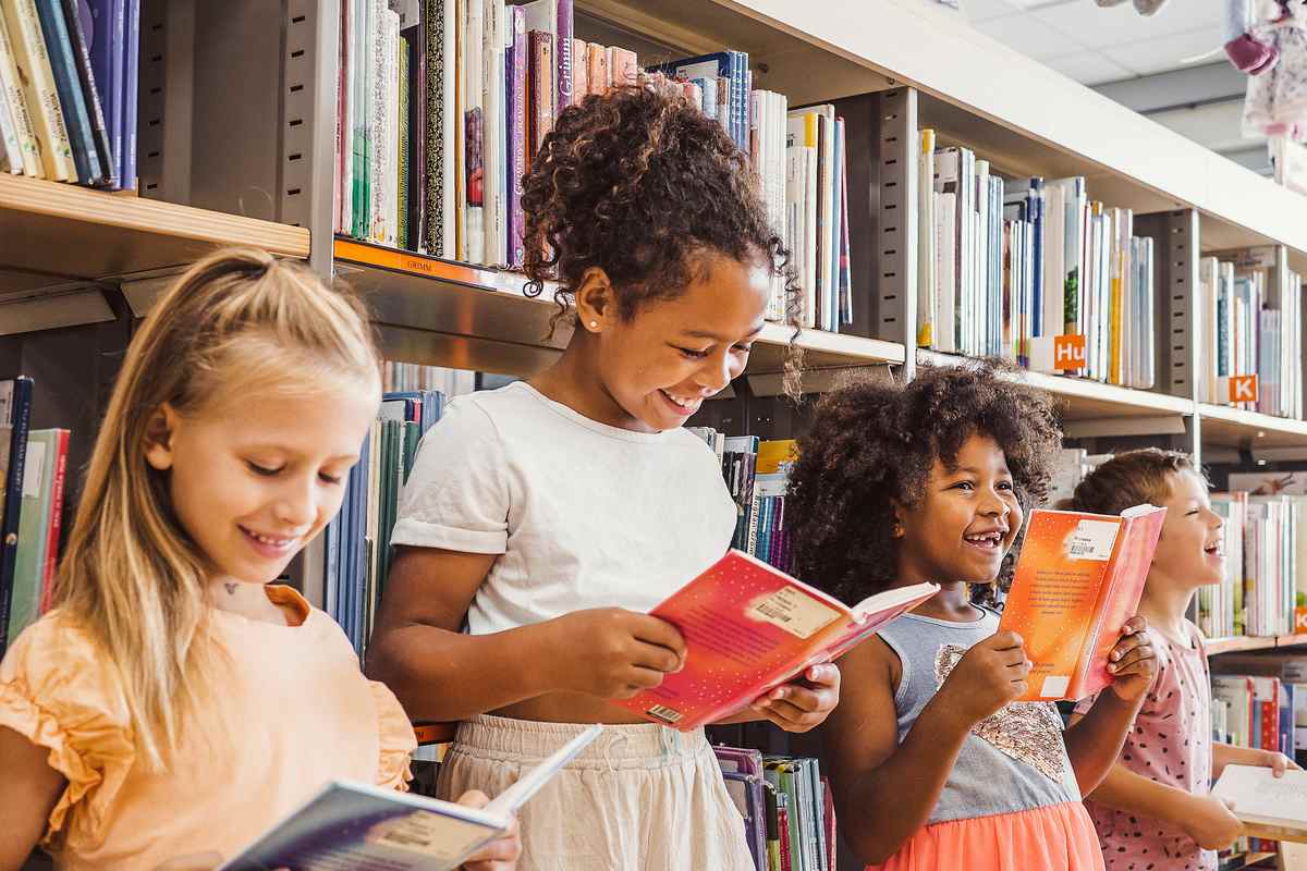 Young children studying abroad, reading books in a school library