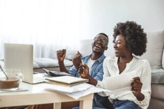 a happy couple reading expat financial advice on their laptop at home