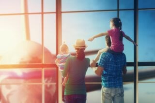 a family with children at an airport looking outside at the place as they prepare for moving abroad