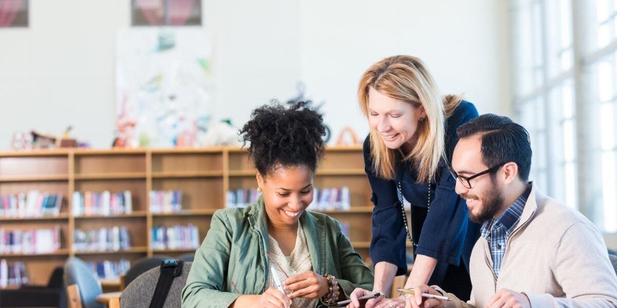 A diverse group of adults studying abroad in a large college library, learning a foreign language