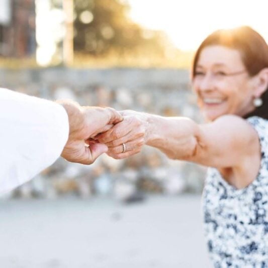 an retired woman smiling and holding her hand out to her partner as she explores one of the best places to retire