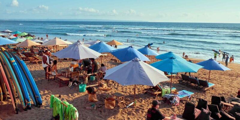 A cluster of colorful beach umbrellas scattered across a beach in Canggu, which has an affordable cost of living in Indonesia