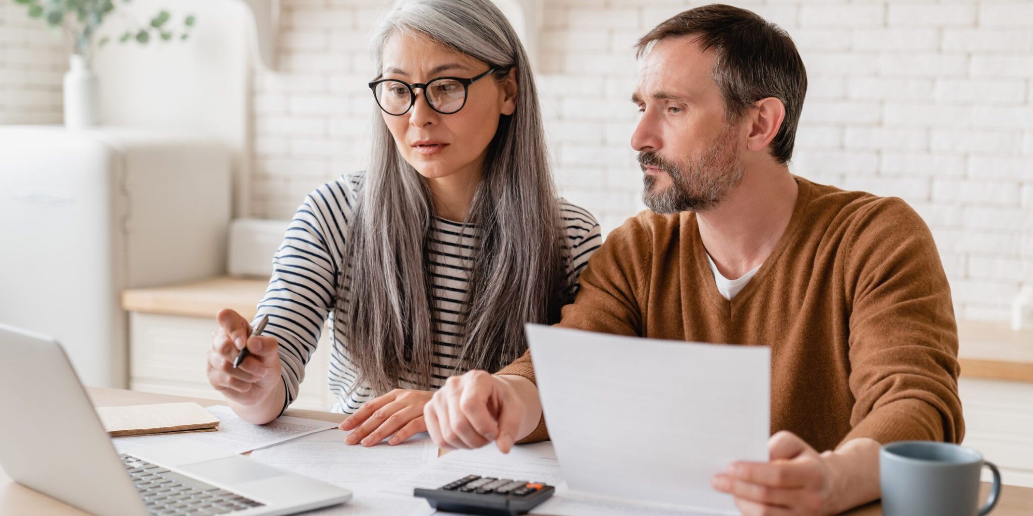 a couple creating a budget on their laptop, having researched expat financial advice for living abroad