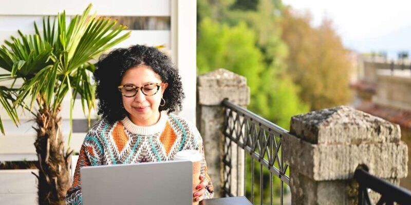 a female digital nomad working on her laptop having secured an Italy work visa