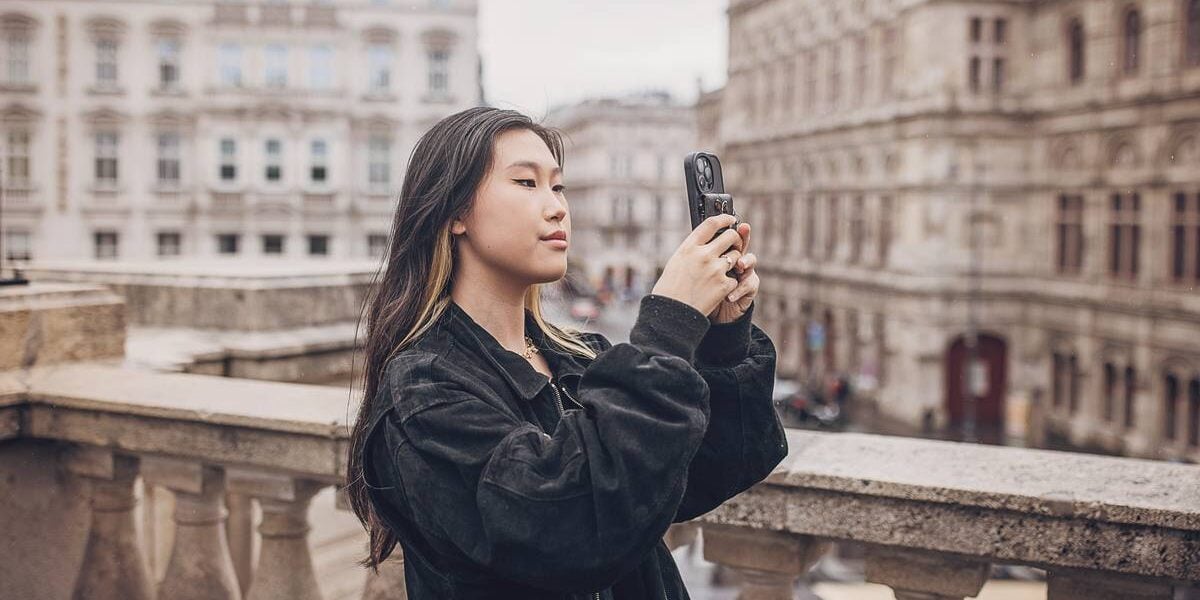 a solo female traveler taking a photo on her phone in the center of Vienna, Austria, one of the safest destinations for solo travel for women