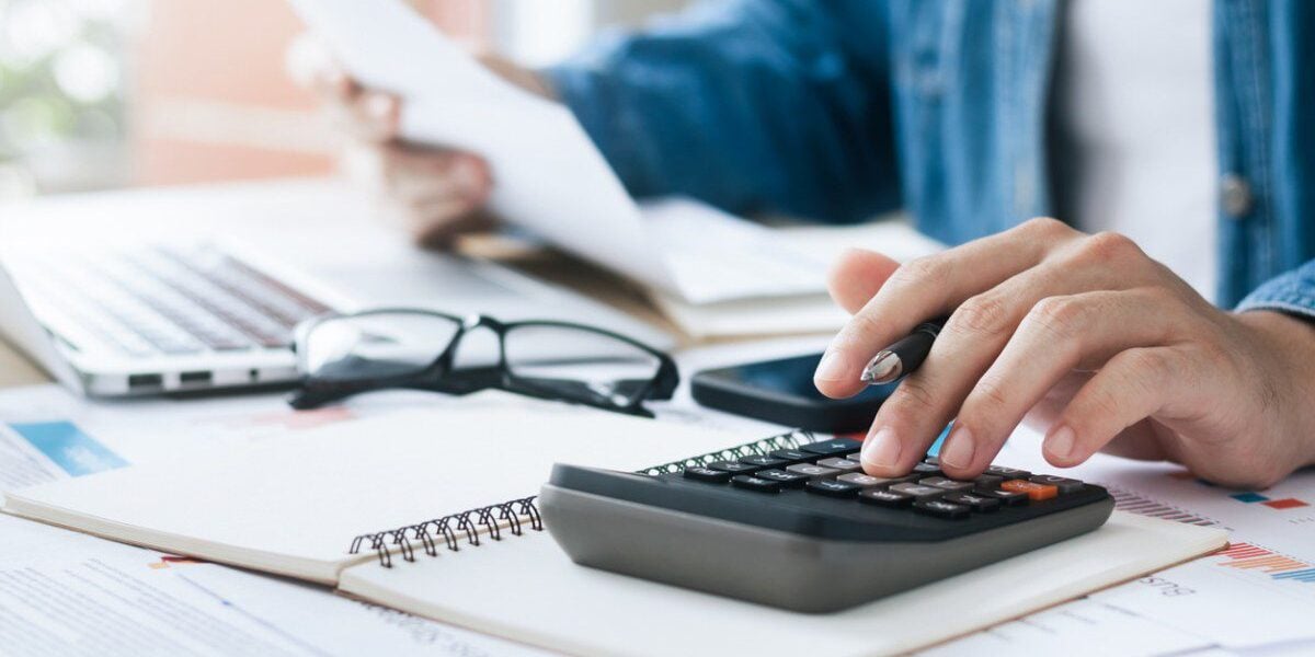 An expat sitting at a desk and using a calculator to file their taxes, seeking expat financial advice to navigate the complexities of managing finances and taxes abroad