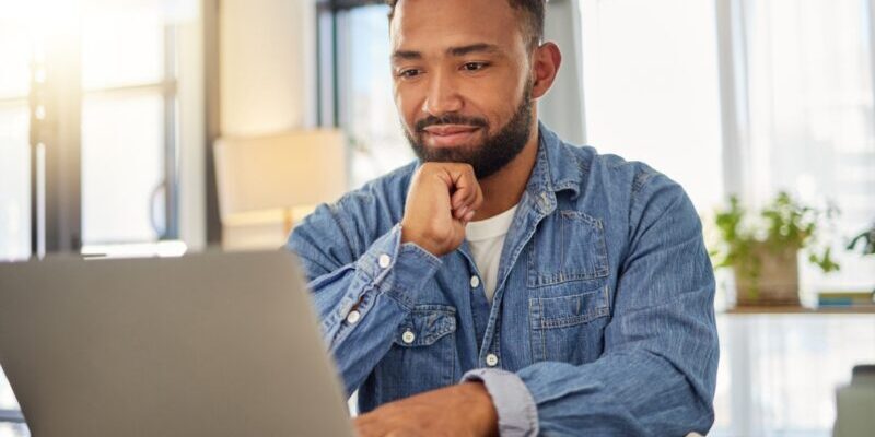 a young man sitting at his laptop applying for a visa as part of his plan for moving to Colombia