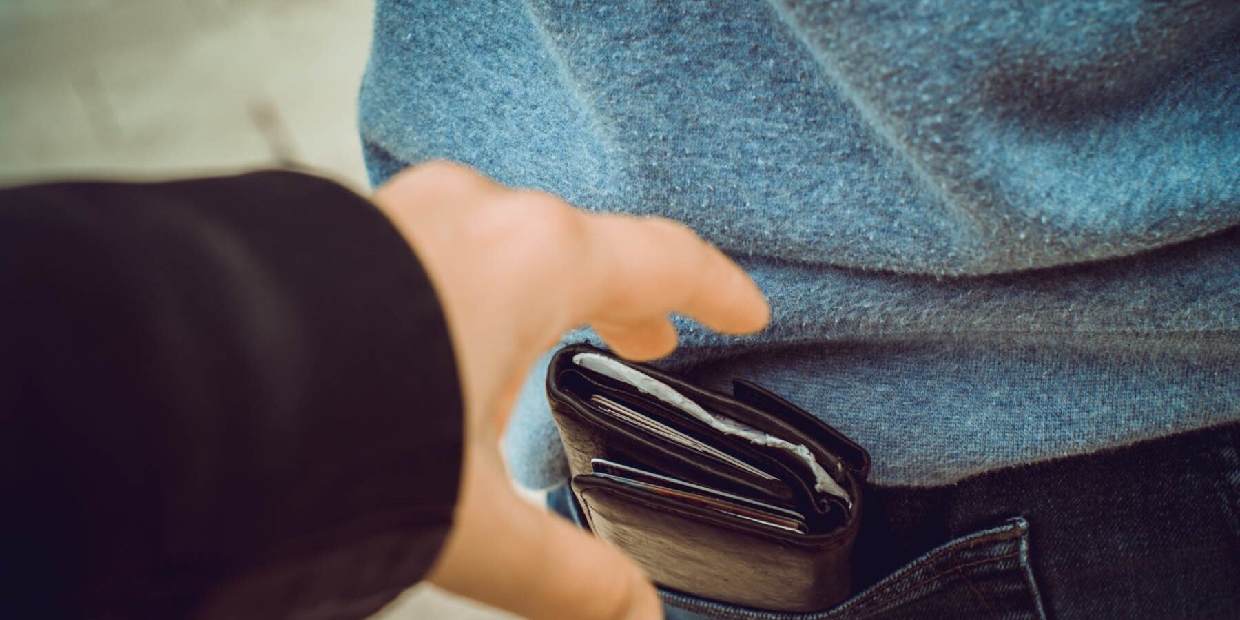 a hand reaching out to steal a wallet containing international credit cards