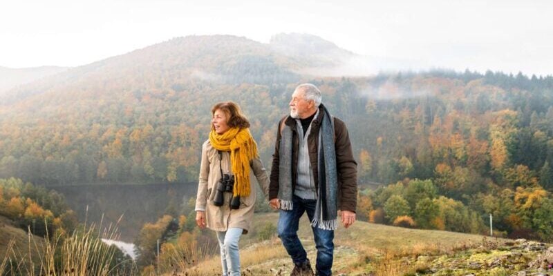 a retired expat couple holding hands and hiking among rolling hills in Slovakia