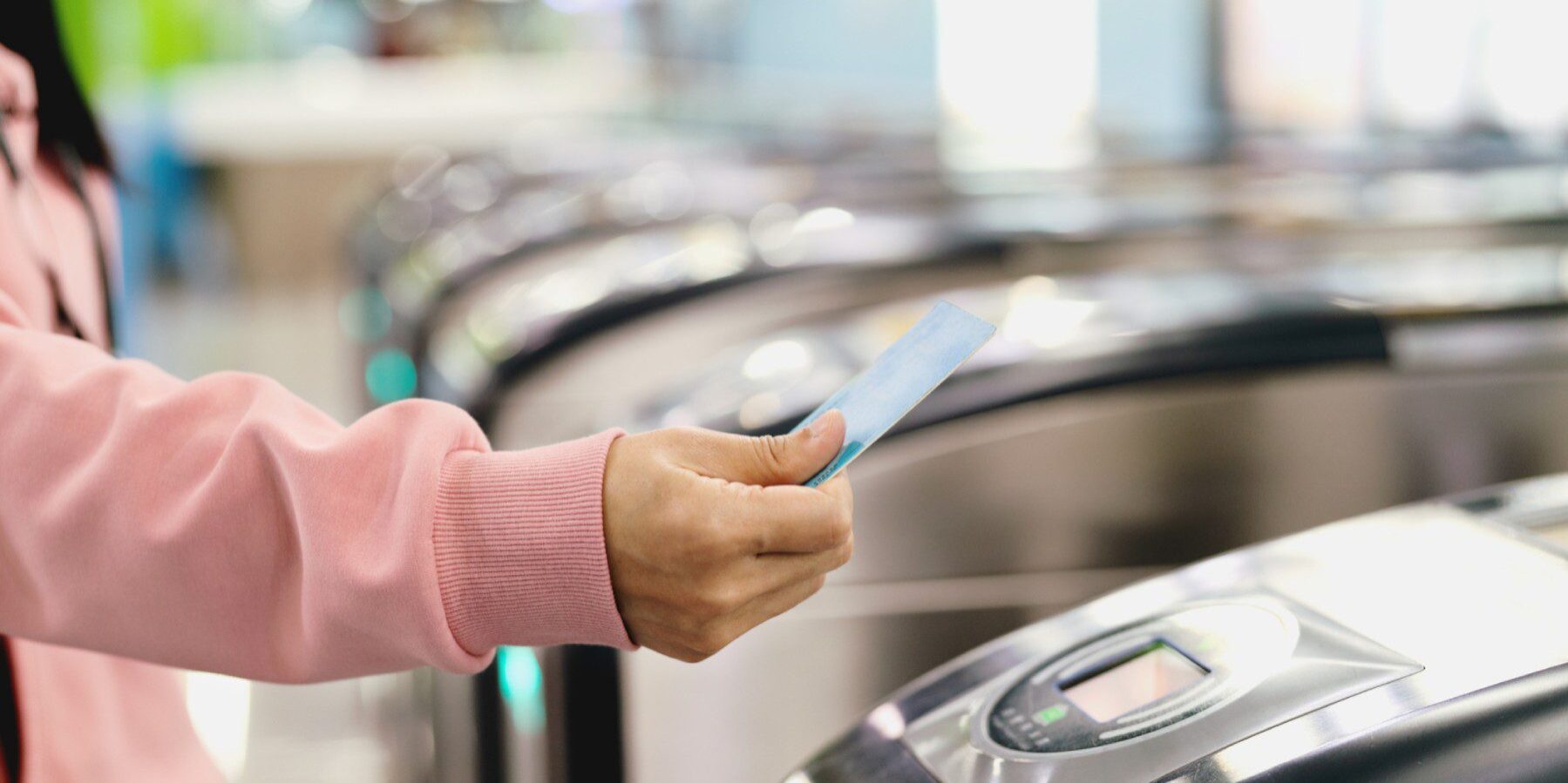 a close-up of a person tapping their travel card against a ticket barrier machine while living abroad