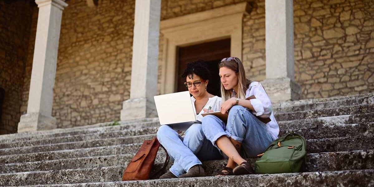 two university students sitting on stairs outside a building on campus in Italy