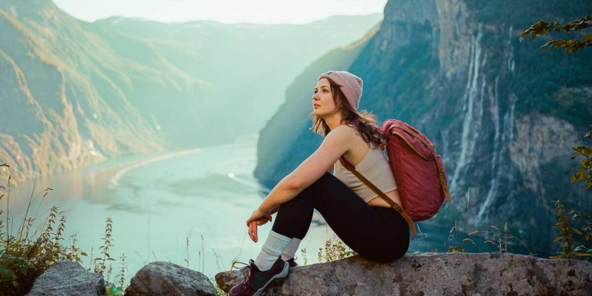 a woman sitting near Seven sisters waterfall in mountains in Norway, one of the best countries for solo travel for women